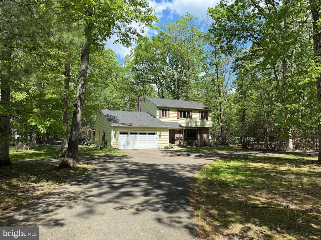 view of front of house with asphalt driveway, an attached garage, and roof with shingles