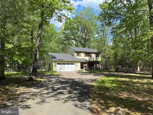 view of front of house with asphalt driveway, an attached garage, and roof with shingles
