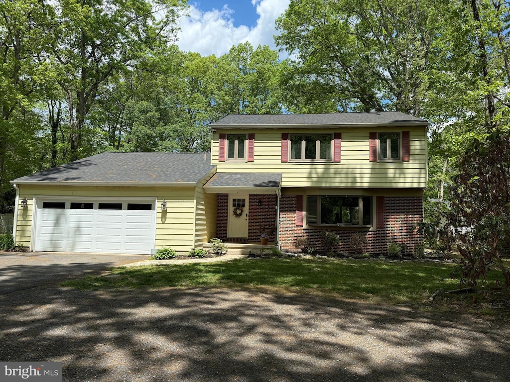 colonial home featuring driveway, an attached garage, and brick siding