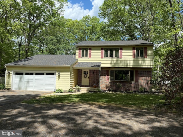 colonial home featuring driveway, an attached garage, and brick siding