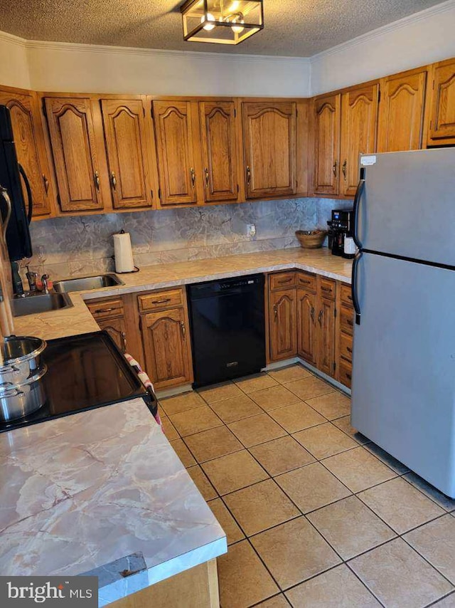 kitchen with brown cabinets, light countertops, light tile patterned flooring, and black appliances
