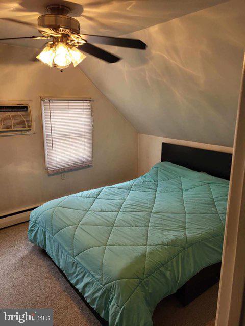 bedroom featuring vaulted ceiling, a ceiling fan, carpet floors, and a wall unit AC