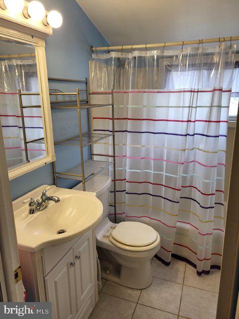 full bath featuring toilet, a shower with curtain, vanity, and tile patterned floors