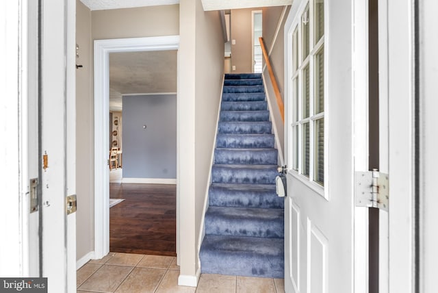 stairway featuring tile patterned floors, baseboards, and a textured ceiling