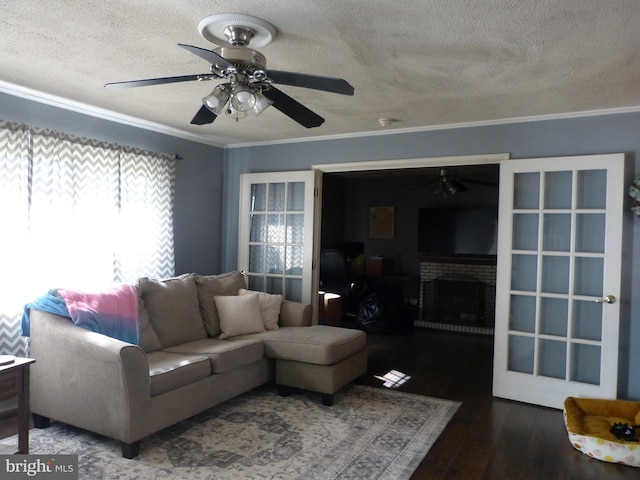 living area with a textured ceiling, wood finished floors, a brick fireplace, ceiling fan, and ornamental molding