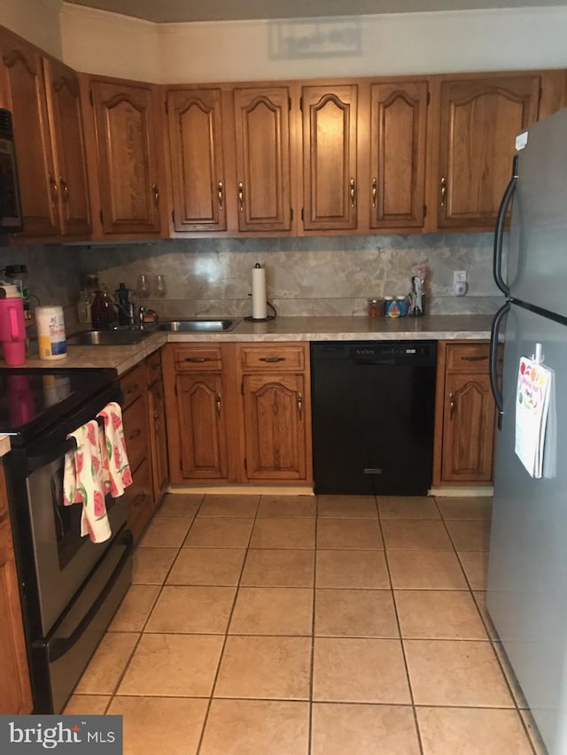 kitchen featuring backsplash, appliances with stainless steel finishes, brown cabinets, light countertops, and light tile patterned floors