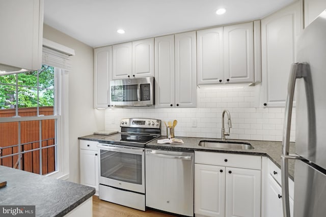 kitchen featuring appliances with stainless steel finishes, a sink, decorative backsplash, white cabinets, and recessed lighting