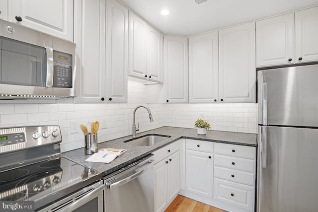kitchen featuring stainless steel appliances, a sink, and white cabinetry
