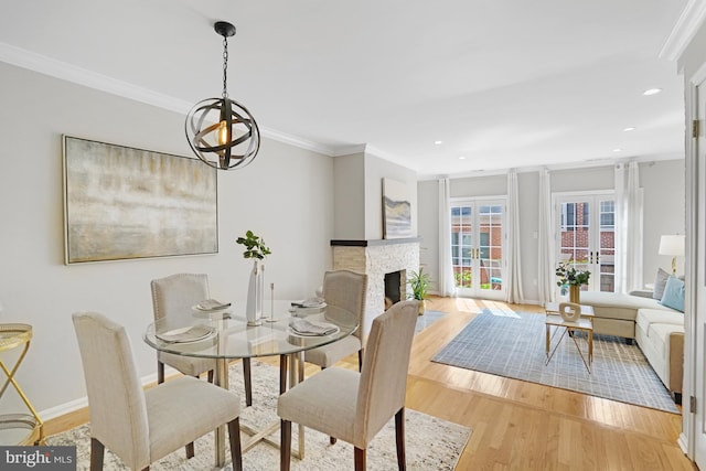 dining space featuring crown molding, light wood-style flooring, recessed lighting, a brick fireplace, and baseboards