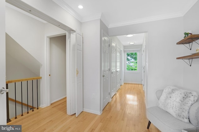 hallway with light wood-style flooring, ornamental molding, an upstairs landing, baseboards, and recessed lighting