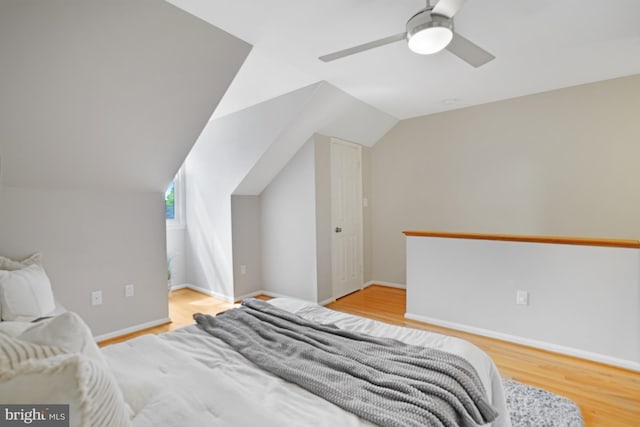 bedroom with wood finished floors, vaulted ceiling, ceiling fan, and baseboards