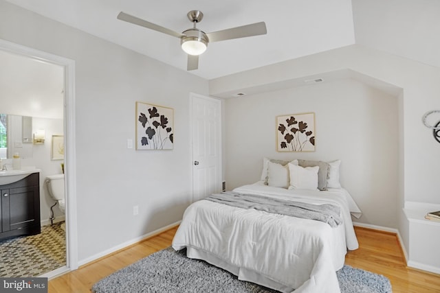 bedroom with light wood-style floors, connected bathroom, baseboards, and ceiling fan