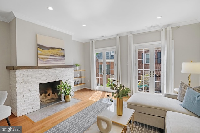 living area with french doors, wood finished floors, crown molding, recessed lighting, and a fireplace with flush hearth