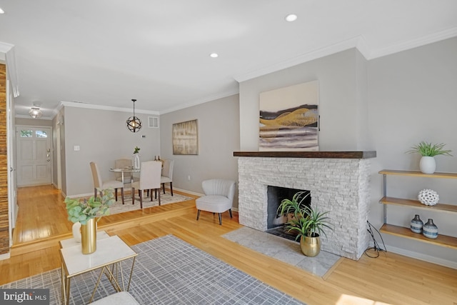 living room featuring wood finished floors, baseboards, ornamental molding, recessed lighting, and a fireplace with flush hearth