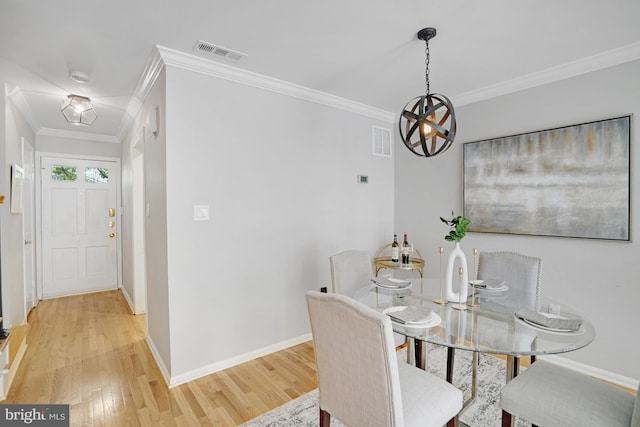 dining room with light wood-type flooring, crown molding, and baseboards