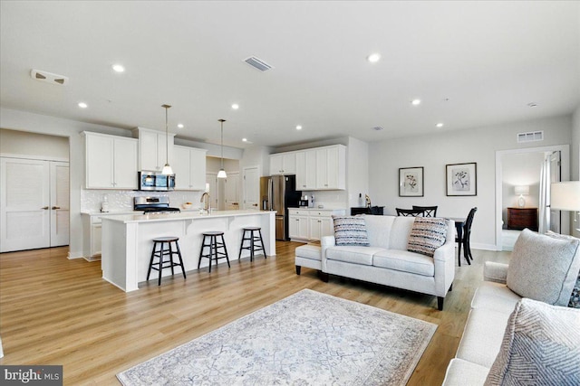 living area featuring light wood-type flooring, visible vents, and recessed lighting