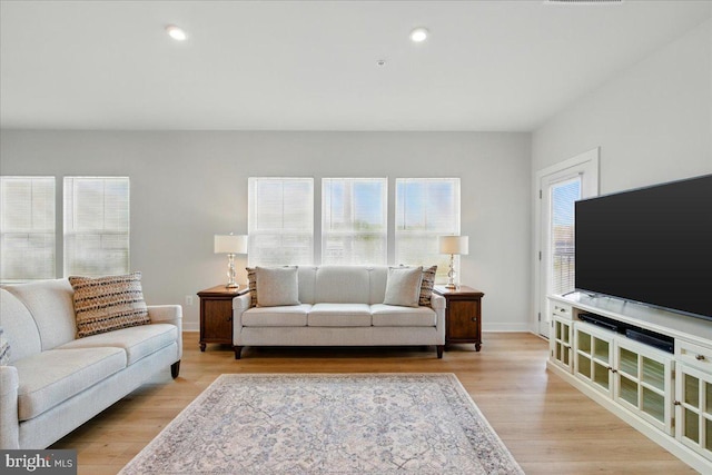 living room with recessed lighting, baseboards, and light wood-type flooring