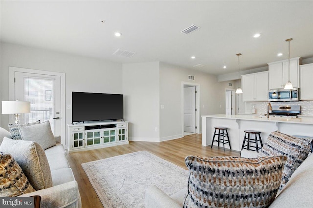 living area with light wood finished floors, baseboards, visible vents, and recessed lighting