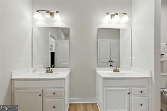 bathroom featuring two vanities, toilet, and a sink