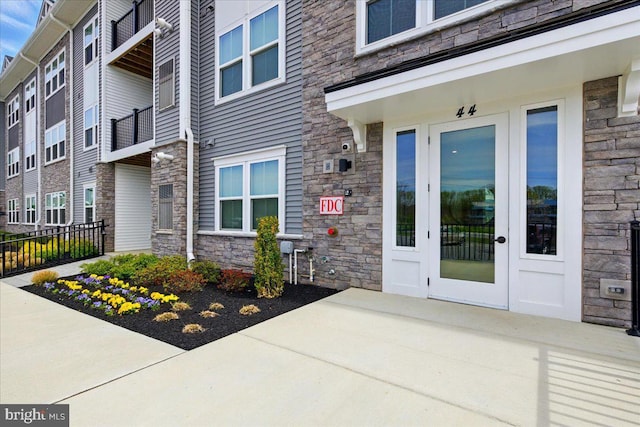 property entrance with stone siding and fence