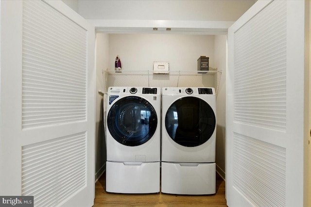 washroom featuring washing machine and clothes dryer, wood finished floors, and laundry area