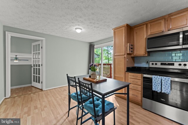 kitchen featuring ceiling fan, backsplash, dark countertops, appliances with stainless steel finishes, and light wood finished floors