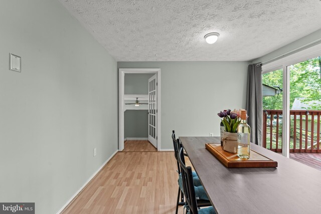 dining room with ceiling fan, a textured ceiling, baseboards, and light wood-style flooring