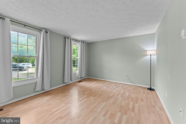 empty room featuring a textured ceiling, baseboards, and wood finished floors