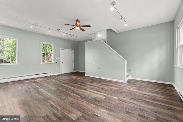unfurnished living room with track lighting, a ceiling fan, stairs, and wood finished floors