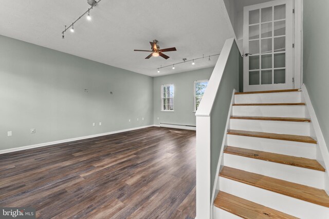 staircase with a ceiling fan, wood finished floors, track lighting, a baseboard radiator, and baseboards