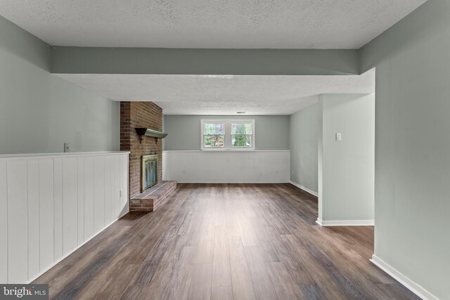unfurnished living room featuring baseboards, a textured ceiling, dark wood finished floors, and a fireplace