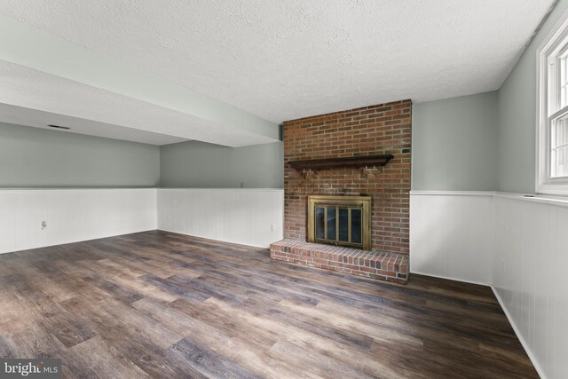 unfurnished living room featuring a textured ceiling, wood finished floors, and a wainscoted wall