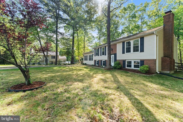 bi-level home featuring a chimney, a front lawn, and brick siding