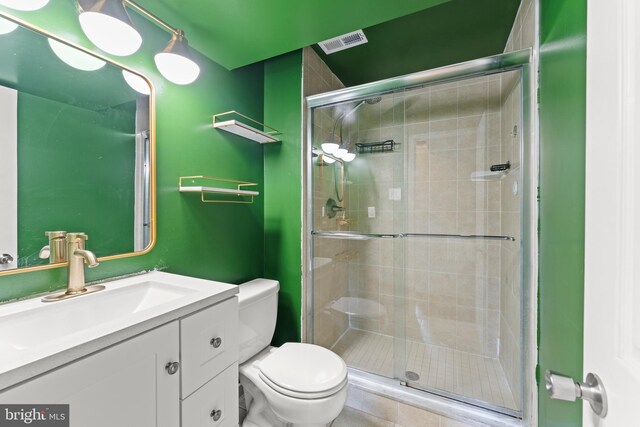 full bathroom featuring vanity, a shower stall, toilet, and visible vents