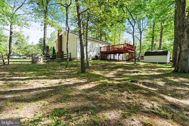 view of yard featuring fence, stairs, a wooden deck, a shed, and an outdoor structure