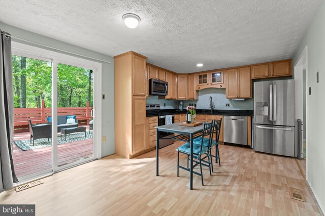 kitchen featuring visible vents, dark countertops, light wood-style floors, a sink, and appliances with stainless steel finishes