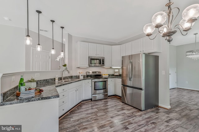 11587 Wollaston Cir, Swan Point, MD 20645 - kitchen with appliances with stainless steel finishes, a sink, a chandelier, wood finished floors, and white cabinets