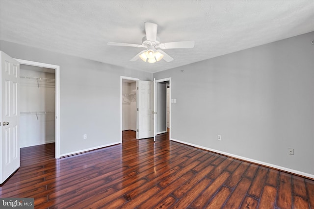 unfurnished bedroom featuring baseboards, ceiling fan, wood finished floors, and a spacious closet