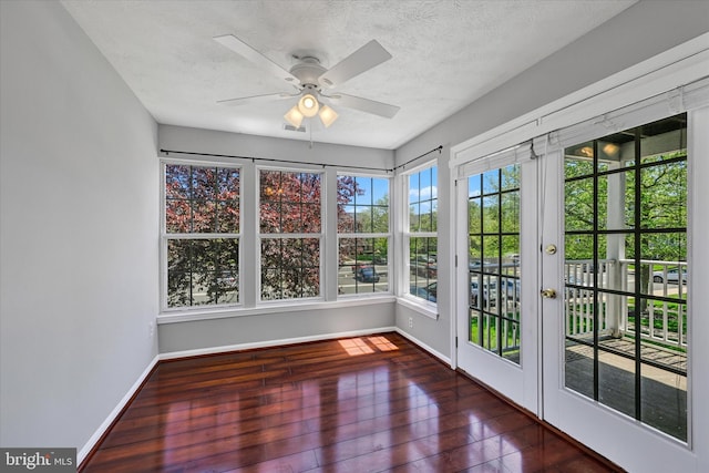 unfurnished sunroom featuring french doors, a textured ceiling, baseboards, and hardwood / wood-style flooring