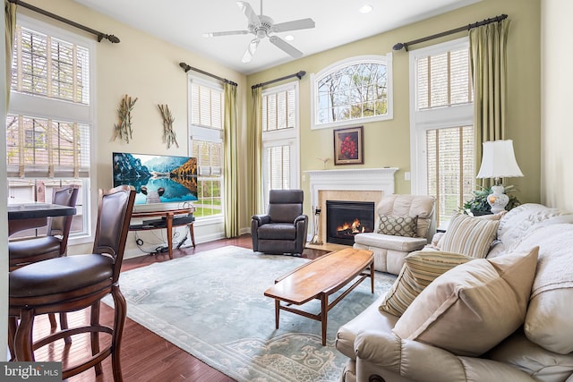 living area featuring a high end fireplace, baseboards, recessed lighting, wood finished floors, and a ceiling fan