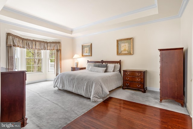 bedroom with a raised ceiling, ornamental molding, and carpet