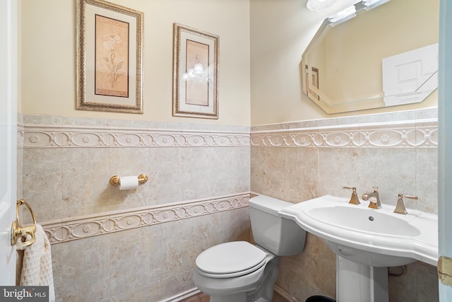bathroom featuring tile walls, wainscoting, and toilet