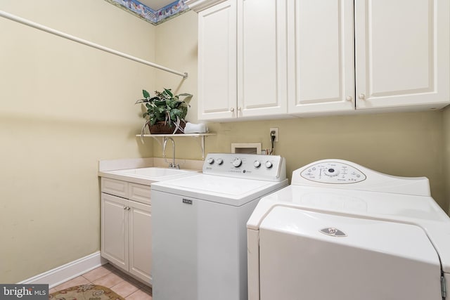 laundry room featuring light tile patterned floors, washing machine and clothes dryer, a sink, baseboards, and cabinet space
