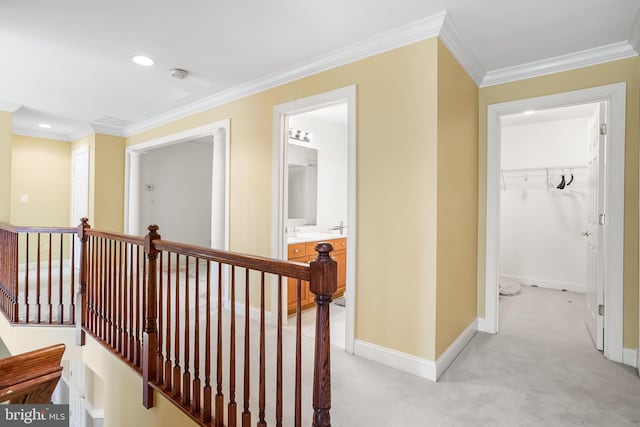 hallway featuring baseboards, ornamental molding, an upstairs landing, and light colored carpet