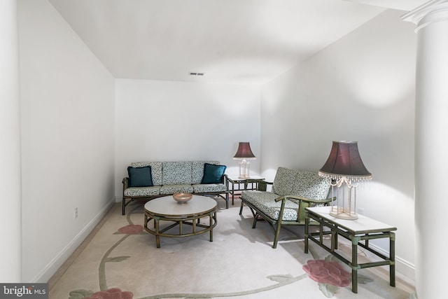 living room featuring ornate columns, visible vents, and baseboards