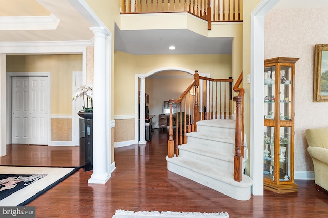 entryway with wood finished floors, arched walkways, and decorative columns