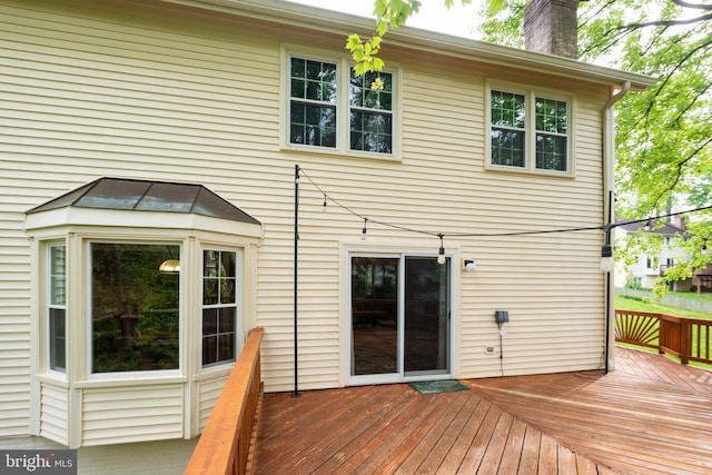 rear view of property featuring a chimney and a deck
