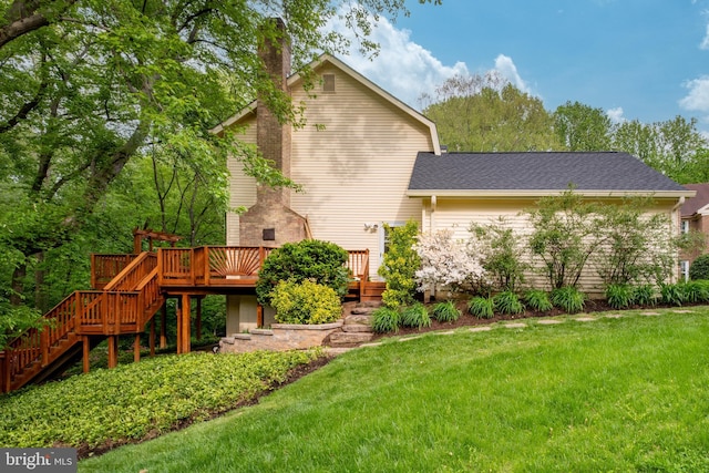 back of house with a chimney, a wooden deck, a yard, a shingled roof, and stairs