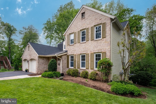 traditional-style house with a garage, a front yard, driveway, and brick siding