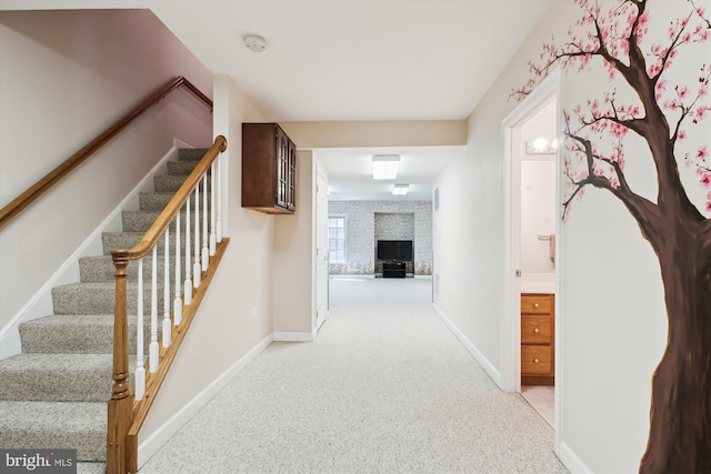hallway with baseboards, carpet, and stairway